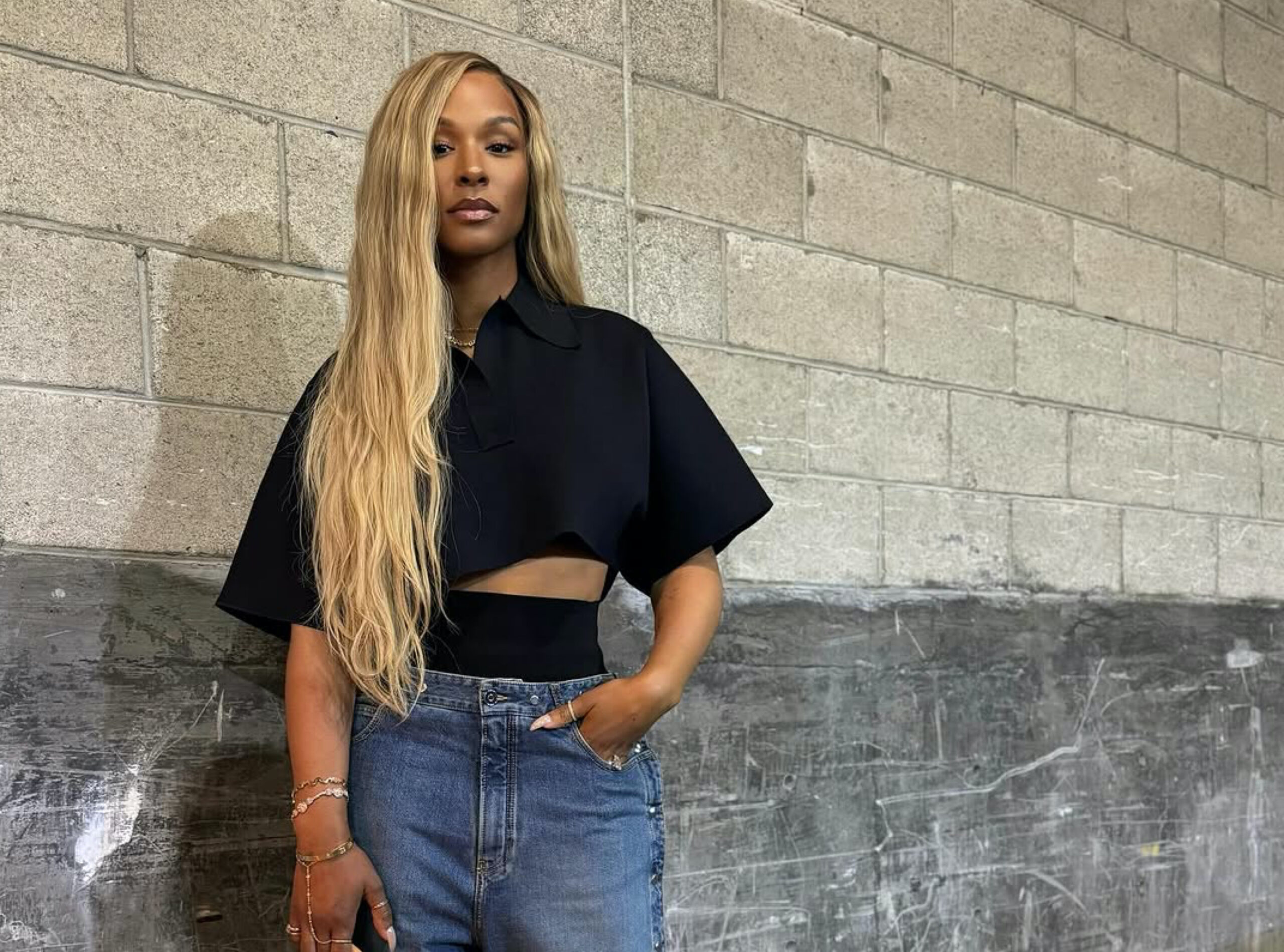 Savannah James Attends Basketball Game in Fashion Swag Savannah James Attends Basketball Game Wearing an Alaia Cropped Black Polo Shirt, Snap Denim Jeans, Louis Vuitton Green Speedy, and Bottega Veneta Mules