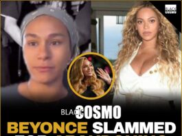 Beyoncé performing on stage with stage crew visible in the background shadows.