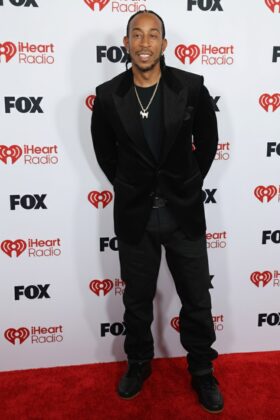 Kehlani stuns in a red satin corset and voluminous Cinderella-style skirt at the 2026 iHeartRadio Music Awards red carpet.