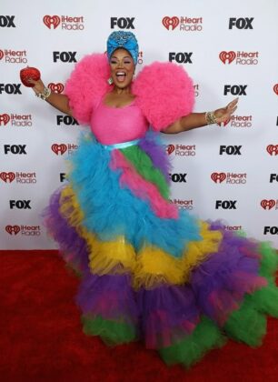 Kehlani stuns in a red satin corset and voluminous Cinderella-style skirt at the 2026 iHeartRadio Music Awards red carpet.