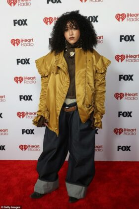 Kehlani stuns in a red satin corset and voluminous Cinderella-style skirt at the 2026 iHeartRadio Music Awards red carpet.