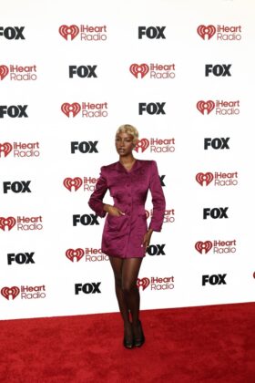 Kehlani stuns in a red satin corset and voluminous Cinderella-style skirt at the 2026 iHeartRadio Music Awards red carpet.