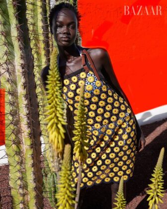 Achol Kuir modeling in the Canary Islands for Harper's Bazaar April 2026, posing against volcanic cliffs in graphic fashion.