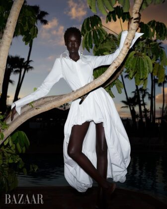Achol Kuir modeling in the Canary Islands for Harper's Bazaar April 2026, posing against volcanic cliffs in graphic fashion.