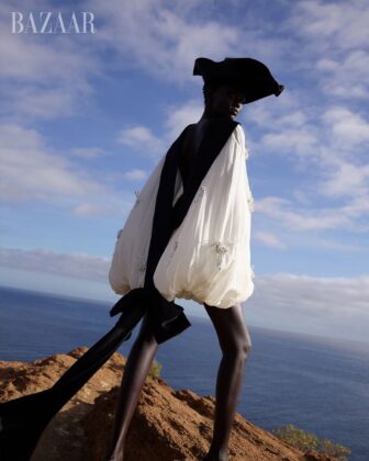 Achol Kuir modeling in the Canary Islands for Harper's Bazaar April 2026, posing against volcanic cliffs in graphic fashion.