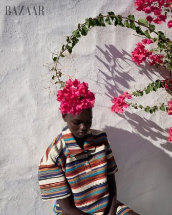 Achol Kuir modeling in the Canary Islands for Harper's Bazaar April 2026, posing against volcanic cliffs in graphic fashion.