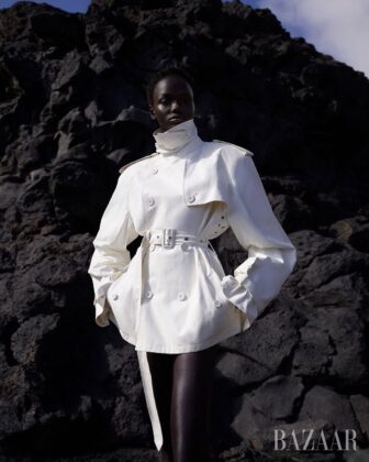 Achol Kuir modeling in the Canary Islands for Harper's Bazaar April 2026, posing against volcanic cliffs in graphic fashion.