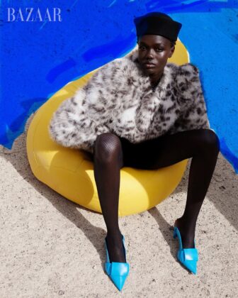 Achol Kuir modeling in the Canary Islands for Harper's Bazaar April 2026, posing against volcanic cliffs in graphic fashion.