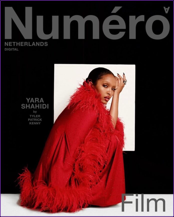 Yara Shahidi Numéro Netherlands June 2026 Cover Feature Yara Shahidi crouches in front of a white backdrop wearing black attire with red feathers for the Numéro Netherlands June 2026 cover.