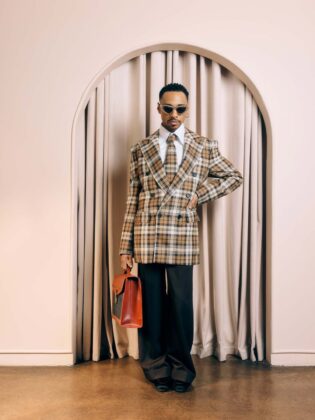 Durand Bernarr posing in a muted lichen green setting with cellular beadwork accessories and textured plumage garments for PAUSE Online June 2026 cover.