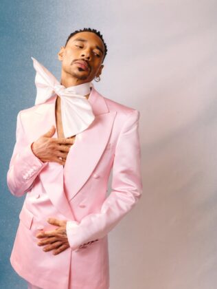 Durand Bernarr posing in a muted lichen green setting with cellular beadwork accessories and textured plumage garments for PAUSE Online June 2026 cover.